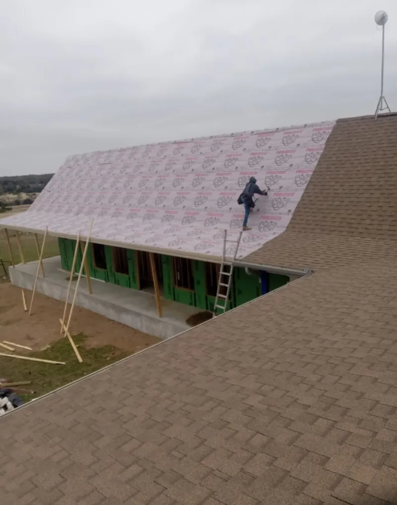 Worker preparing underlayment for a metal roof installation in Cicero